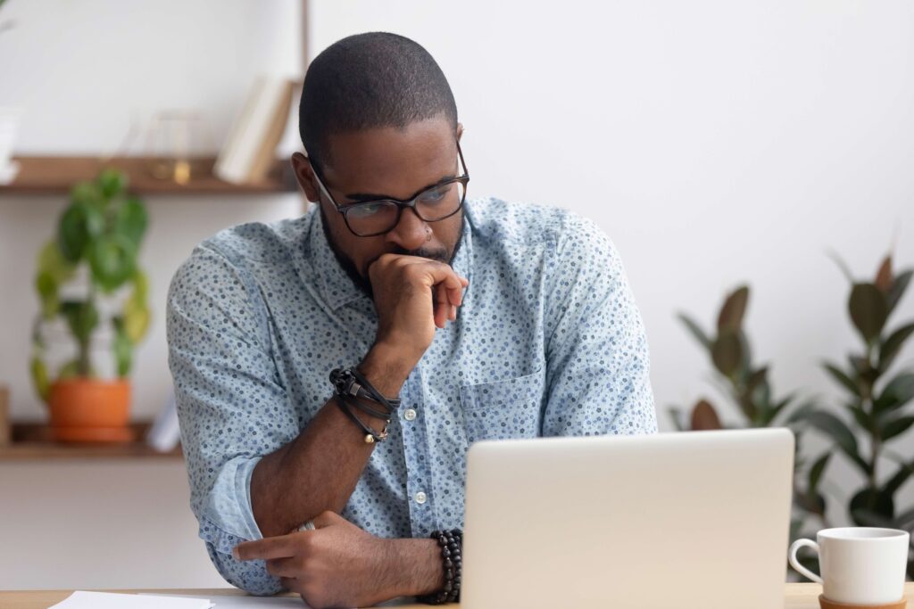 A Stressed man with a laptop who’s loan application has been affected by his bad credit score.