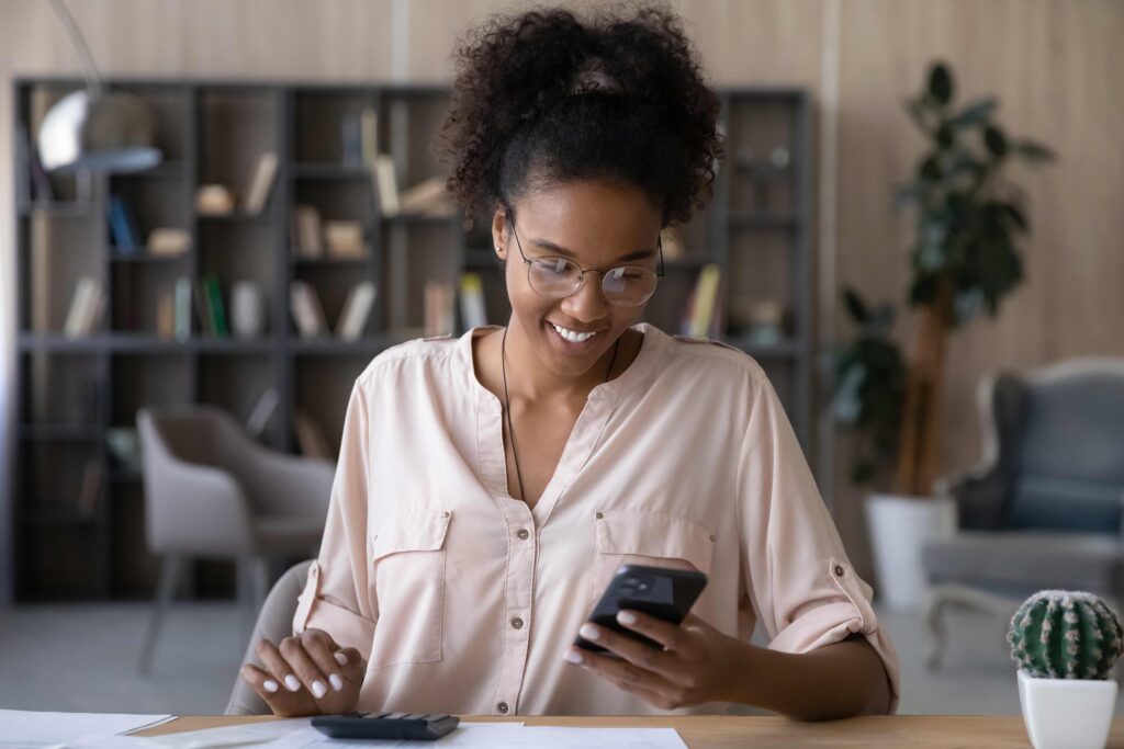 A woman seated in front of her laptop with a smile on her face. The article discusses different ways to get more money.