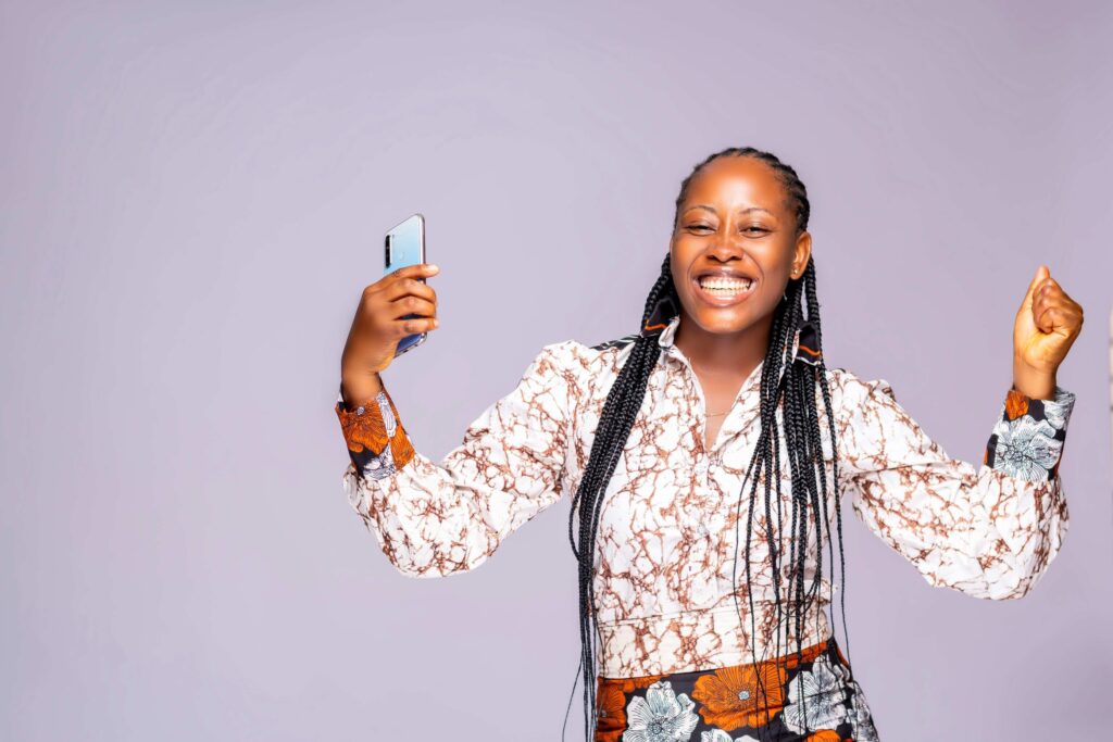 A smiling woman holding a phone, indicating her successful loan approval. The image pertains to the topic of "How loans are approved."